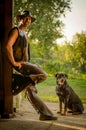 Cowboy stands with dog at the barn. A handsome man with a hat. A sympathetic man.