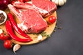 Cowboy steak recipe. Raw ribeye beef steak ready for grilling with seasonings and chili pepper on wooden cutting board Royalty Free Stock Photo