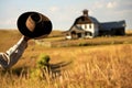 cowboy tipping hat, farmhouse and barn visible behind