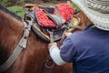 Cowboy tying horse saddle to untrained mare