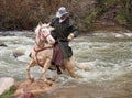 Cowboy on white horse crossing dangerous river Royalty Free Stock Photo