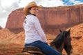 Cowgirl wearing straw hat riding horse in Monument Valley Royalty Free Stock Photo