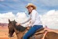 Cowgirl wearing straw hat riding horse in Monument Valley Royalty Free Stock Photo