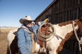 Cowboy wrangler with white hat portrait with saddled paint horse ready to ride