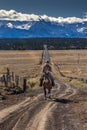 Cowboys on Cattle Drive on long dirt road to San Juan Mountains