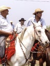 Cowboys mounted on Quarter Horses prepare for the lasso test on a dirt track