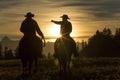 Cowboys riding across grassland early moring, British Colombia,