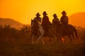 Cowboys are riding horses silhouette in sunset with mountain Royalty Free Stock Photo