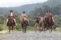 Cowboys in traditional wear riding on a country road