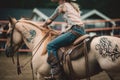 cowgirl, with cherry blossom tattoos and chaps, riding a bucking bronco