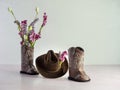 Cowgirl or cowboy brown hat with cowgirl or cowboy brown leather boots with one boot filled with pink and purple artificial