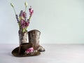 Cowgirl or cowboy brown hat with cowgirl or cowboy brown leather boots with one boot filled with pink and purple artificial