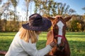 Woman with cowboy hat is talking to her young horse at farm Royalty Free Stock Photo