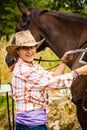 Cowgirl getting horse ready for ride on countryside Royalty Free Stock Photo