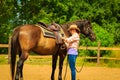 Cowgirl getting horse ready for ride on countryside Royalty Free Stock Photo