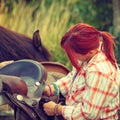 Cowgirl getting horse ready for ride on countryside Royalty Free Stock Photo