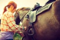 Cowgirl getting horse ready for ride on countryside Royalty Free Stock Photo