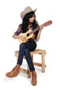Cowgirl plays ukulele on a chair Royalty Free Stock Photo