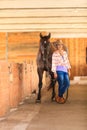 Cowgirl standing next to brown horse friend Royalty Free Stock Photo