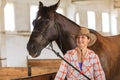 Cowgirl standing next to brown horse friend Royalty Free Stock Photo