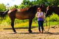 Cowgirl standing next to brown horse friend Royalty Free Stock Photo