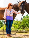 Cowgirl standing next to brown horse friend Royalty Free Stock Photo