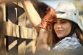 Cowgirl in stetson next to wooden fence