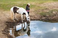Cowgirl woman watering her horse in a pond