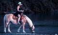 Teen girl on a horse in the water. Cowgirl woman watering her horse in a river Royalty Free Stock Photo