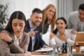 Coworkers bullying their colleague at workplace in office Royalty Free Stock Photo