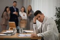 Coworkers bullying colleague at workplace in office, space for text Royalty Free Stock Photo