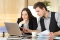 Coworkers checking laptop content together at office