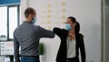 Coworkers with face mask touching elbow with his collegue