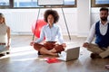 Coworkers practicing meditation at work. Coworkers sitting on the floor with computer and work notes Royalty Free Stock Photo