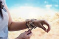 Cowrie shell bracelets on the wrist of woman on beach background Royalty Free Stock Photo