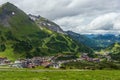 Cows grazing on an alpine meadow in the background houses, roads, ski lifts in alpen ski resort Obertauern in summer