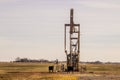 Cows out in a winter field around an oil well with another well and houses on the flat horizon Royalty Free Stock Photo