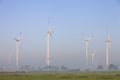 Cows and wind turbines in morning mist on german countryside of lower saxony Royalty Free Stock Photo