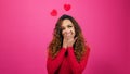 Coy and flirty young woman giggles at secret admirer, Valentines Day studio pink