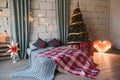 Coziness, comfort, interior and holidays concept - cozy white loft bedroom with bed and christmas garland lights and