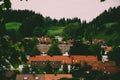 Cozy alpine houses with wooden roofs lost in green rainy valley among mountains.