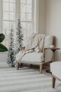 Cozy armchair situated with a blanket draped on it in the corner of a room near a window Royalty Free Stock Photo