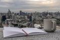 Cozy atmosphere with Evening coffee with a city view. There is a cup of coffee, hourglass, diaries, notebook, pencil to record Royalty Free Stock Photo