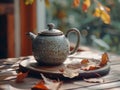 Cozy Autumn Atmosphere with Ceramic Teapot on Wooden Table Amidst Fallen Leaves and Warm Natural Light