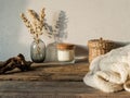 Cozy autumn home still life of dry flowers in vase, straw box, glass candle, knitted blanket on a rustic wooden table and shadows Royalty Free Stock Photo