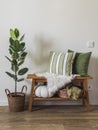 Cozy autumn interior of the hallway - a wooden bench with decorative pillows, a basket with blankets and a homemade ficus flower