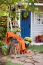Cozy Autumn patio with chair, plaid, plants, wooden lantern, potted chrysanthemums. Halloween. Decorations in backyard for relax i Royalty Free Stock Photo