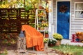 Cozy Autumn patio with chair, plaid, wooden lantern, potted chrysanthemums and pumpkins. Halloween. Decorations in backyard for re