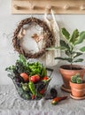 Cozy autumn still life in the hallway - a basket with seasonal vegetables, a ficus flower, a wreath of vines, a wooden shelf. Royalty Free Stock Photo