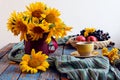 Cozy autumn tea party: a cup of tea, a bouquet of sunflowers, fruits on a wooden table